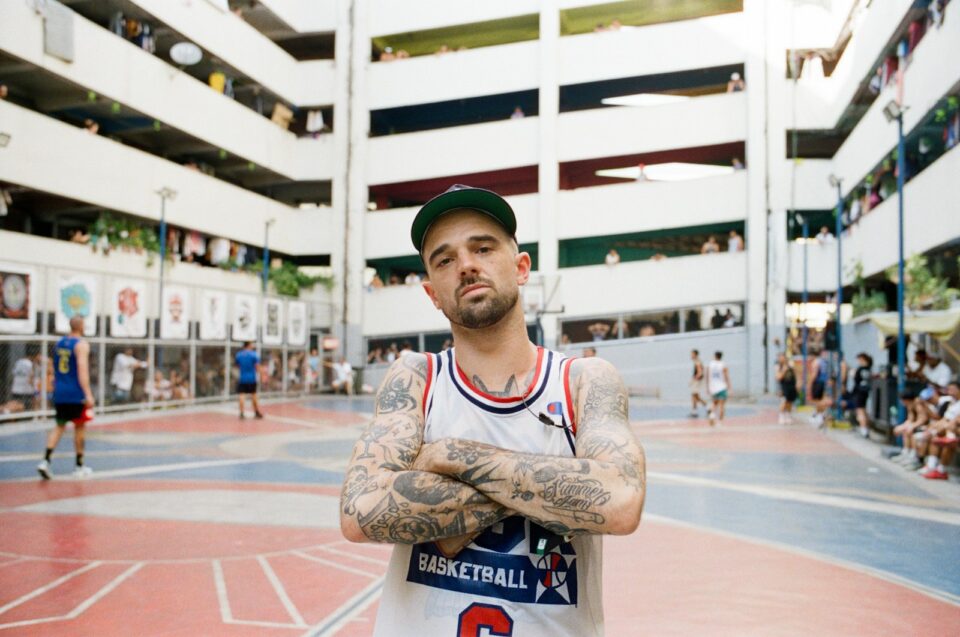 A man with tattoos standing on a basketball court